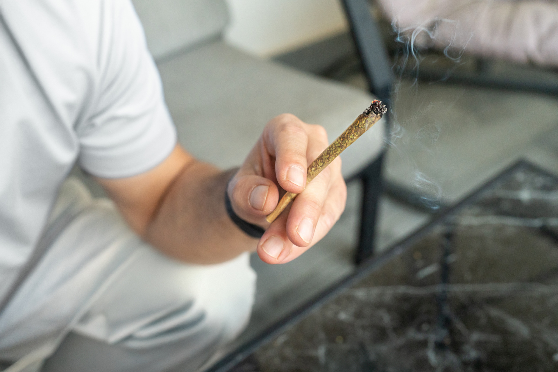 A closeup shot of a woman passing a THCA joint to her friend.