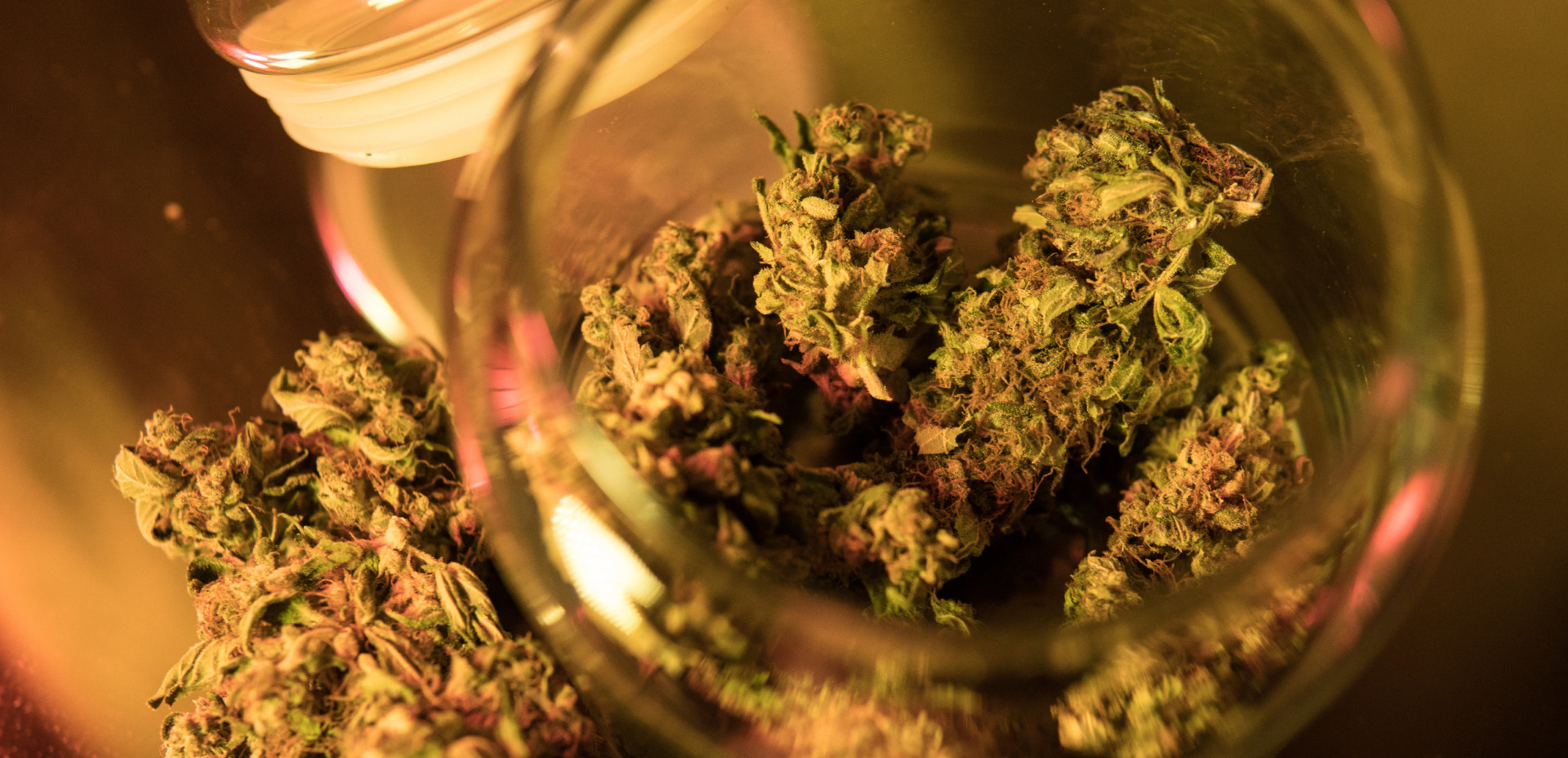 THCA buds in a glass jar, cannabis on a rolling paper.